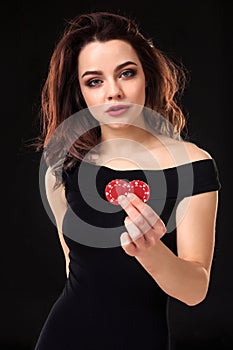 Smiling girl holding a gambling chips in her hands on black background.