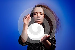 Smiling girl holding a glowing ball in her hands. Blue background