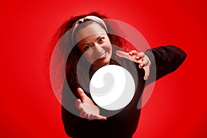 Smiling girl holding a glowing ball in her hands Red background