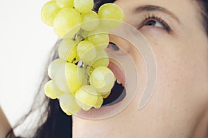 Smiling girl holding grapes near her face and smiling broadly to the viewer