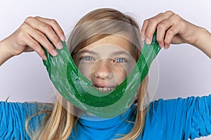 Smiling girl holding a green slime toy in front of her face