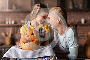 Smiling girl holding jack o lantern sitting near her mother