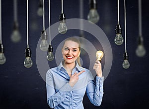 Smiling girl holding a light bulb shining