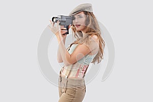 Smiling girl holding an old-fashioned retro video camera, dressed in vintage style. Video maker service or influencer social media