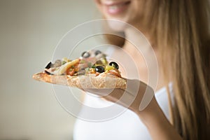 Smiling girl holding a slice of pizza in her hand