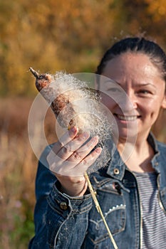 A smiling girl holds a cattail in her hand.
