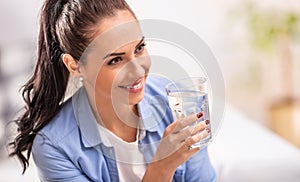 Smiling girl holds a glass of pure water in her hand
