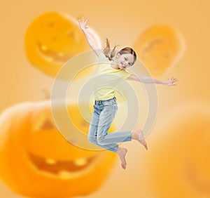 Smiling girl jumping over pumpkins background