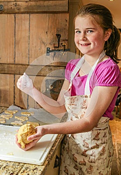 Smiling girl kneading biscuit (cookie) mixture.