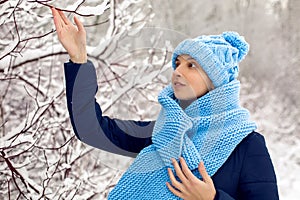 Smiling girl in a knitted blue scarf, and cap stands