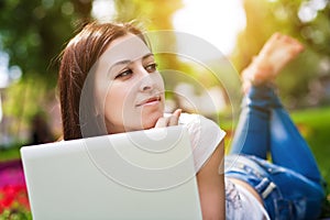 Smiling girl laying on grass with laptop