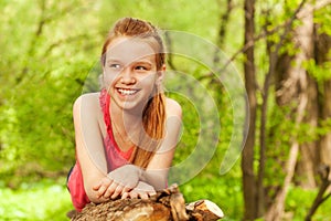 Smiling girl laying on the log at sunny day