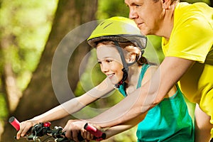 Smiling girl learning to ride with her father
