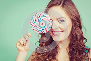 Smiling girl with lollipop candy on teal