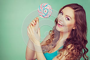 Smiling girl with lollipop candy on teal