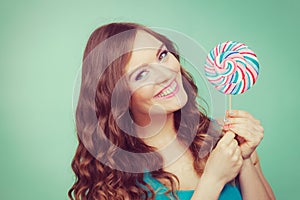 Smiling girl with lollipop candy on teal