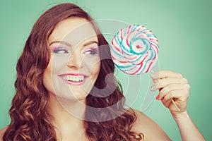 Smiling girl with lollipop candy on teal