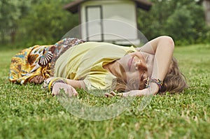 Smiling girl lying on green grass and enjoying summer heat