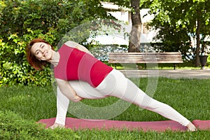 Smiling girl in the park exercise on the yoga mat, high lunge