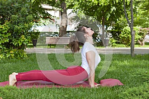 Smiling girl in the park exercise on the yoga mat, high lunge