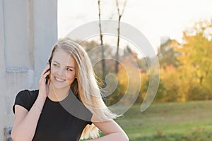 Smiling girl is phoning standing on the bridge and looking at the sid