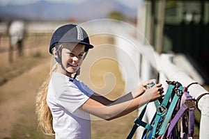 Smiling girl picking up a horse muzzle in the ranch