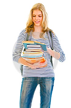 Smiling girl with pile of schoolbooks reading