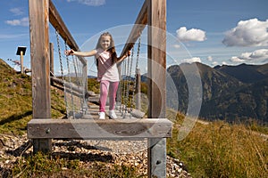 Smiling girl in pink deftly moves on suspended logs to train balance