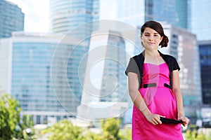 Smiling girl in pink dress with tablet pc stands