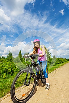 Smiling girl in pink helmet ready to ride a bike