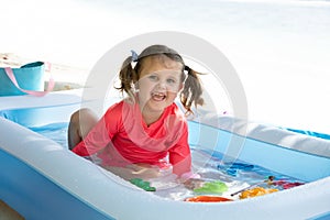 Smiling Girl Playing In The Inflatable Pool On Beach