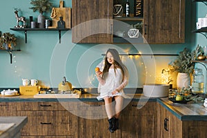 Smiling girl playing with tangerines. Cozy home holiday Christmas in the kitchen