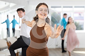 Smiling girl practicing swing dance with partner in choreographic studio