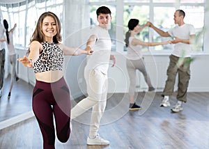 Smiling girl practicing swing with partner in dance studio