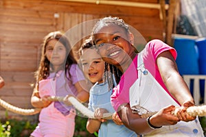 Smiling girl pull rope with friends in competition