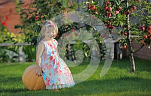 Smiling girl on pumpking over apple tree on a farm