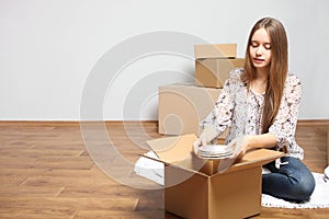 Smiling girl puts plates in empty box