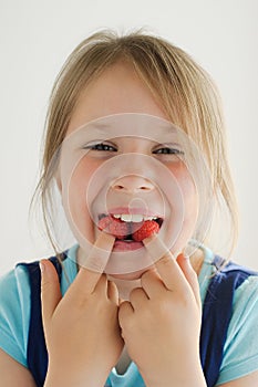 The smiling girl with raspberries in her mouth