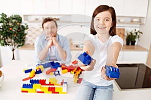 Smiling girl reaching out two construction set pieces