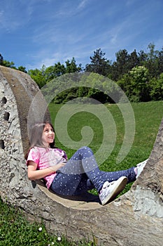 Smiling Girl Resting On The Stonewall And Daydreaming In The Park At Sunny Spring Day