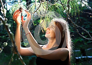 Smiling girl rips a lump from a cedar branch in the summer Siberian taiga