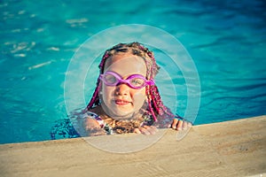 Smiling girl in rose-colored glasses for swimming in the pool