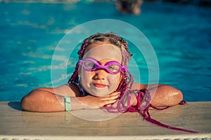 Smiling girl in rose-colored glasses for swimming in the pool