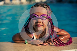 Smiling girl in rose-colored glasses for swimming in the pool