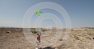 A smiling girl runs with a kite while playing in the fresh air.