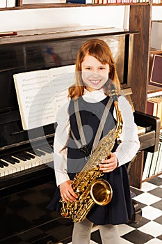 Smiling girl in school uniform with alto saxophone