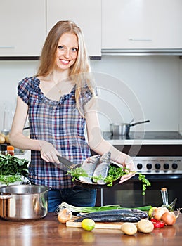 Smiling girl with seabass fish in fryingpan