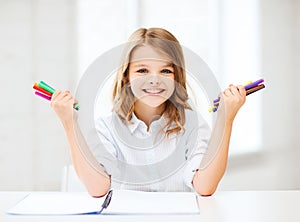 Smiling girl showing colorful felt-tip pens