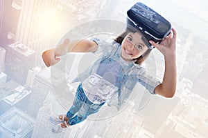 Smiling girl showing thumbs up while removing VR headset