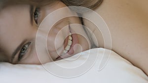 Smiling girl in a silk nightie lying on pillow